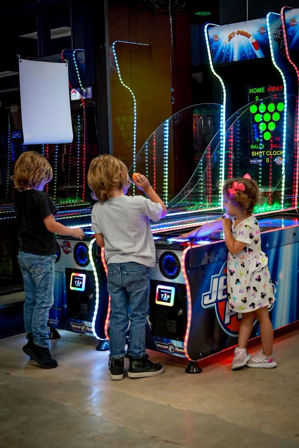 Kids playing arcade games at Sol's Arcade + Taproom